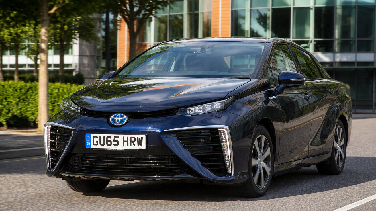 Blauer Toyota Mirai Wasserstoff-Brennstoffzellenwagen fährt auf städtischer Straße bei Tageslicht.